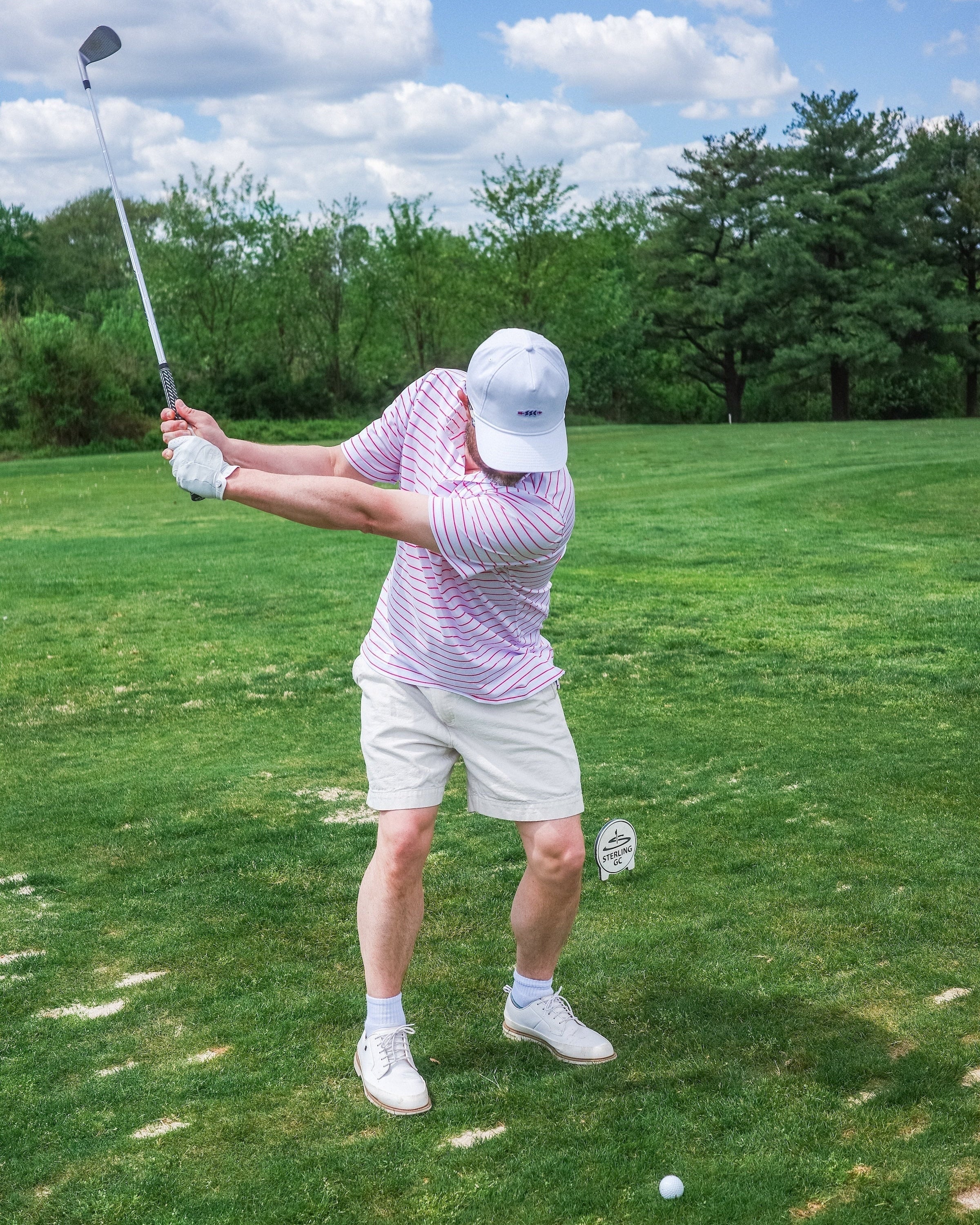 Person playing golf on a green course with trees in the background