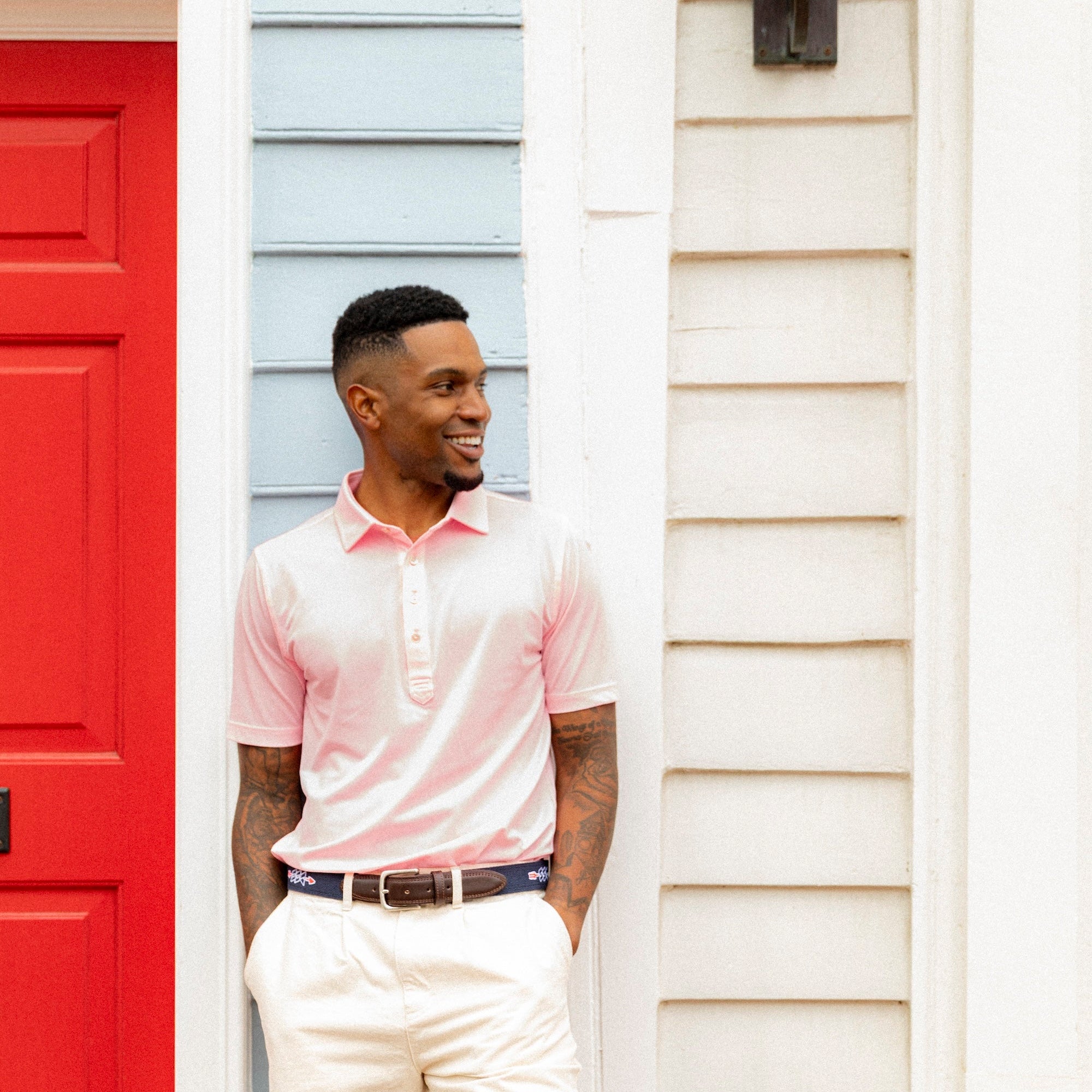 Man standing on a porch with a red door and white siding.