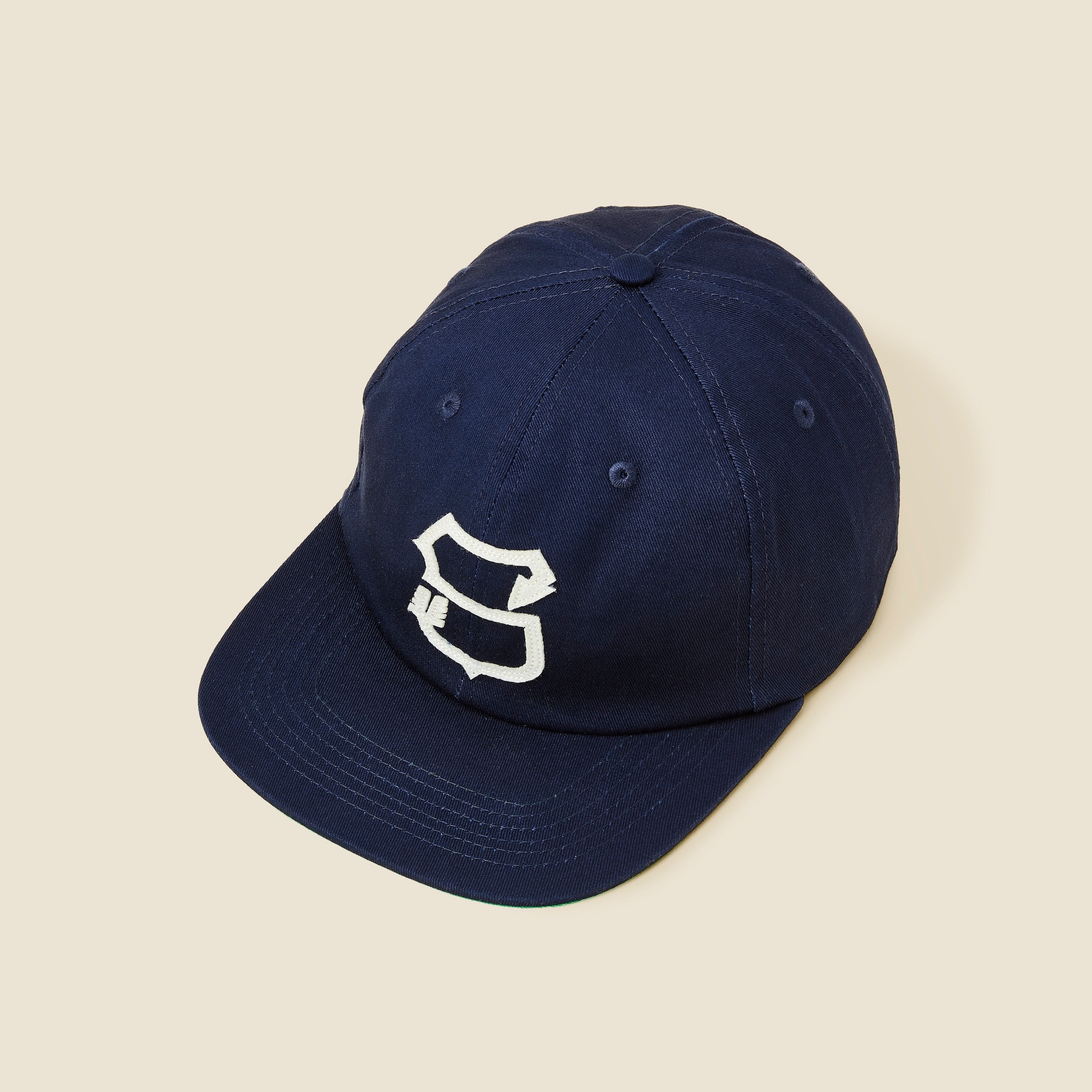 Navy blue cap with a white logo on a beige background