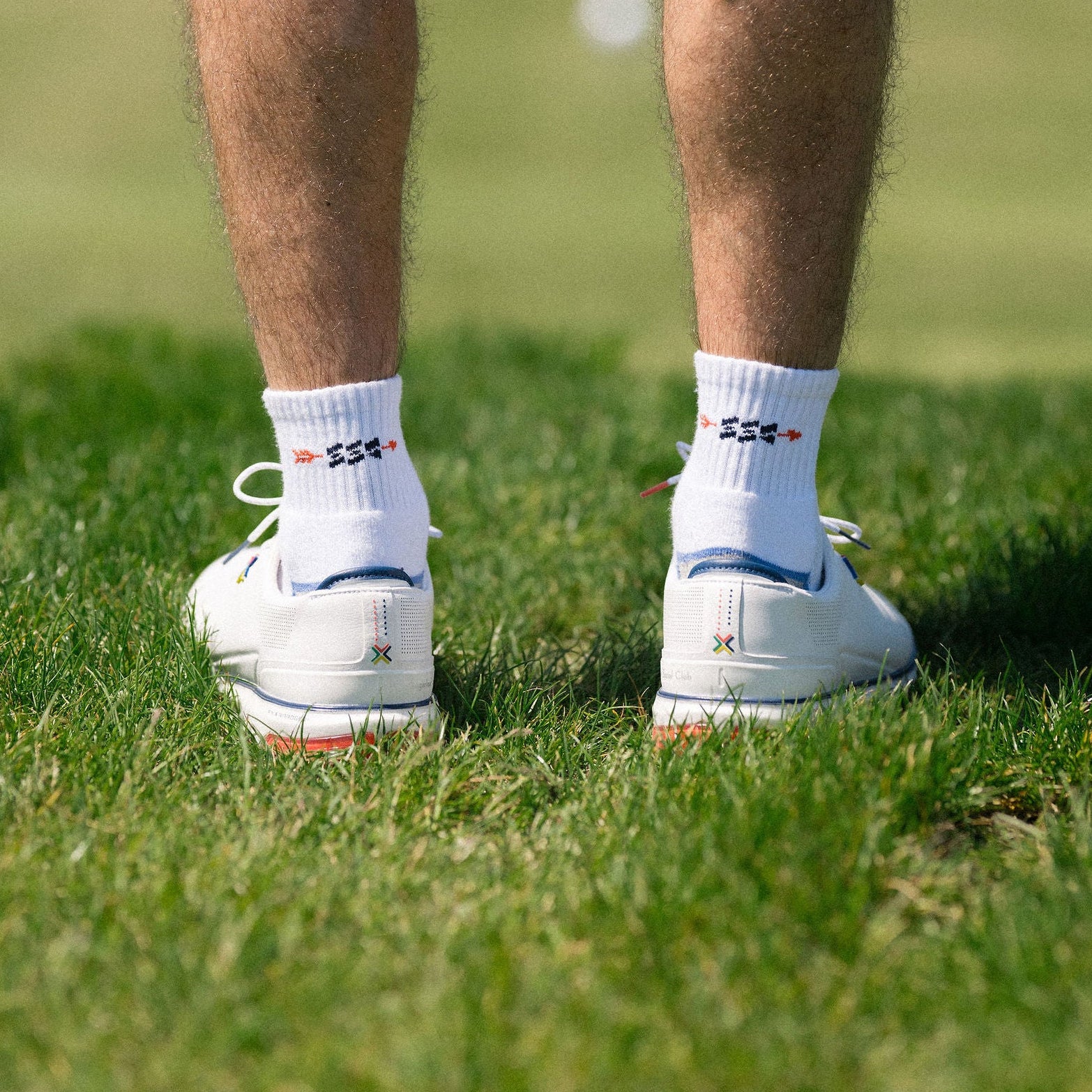 Person wearing blue shorts and white golf shoes on a grassy field