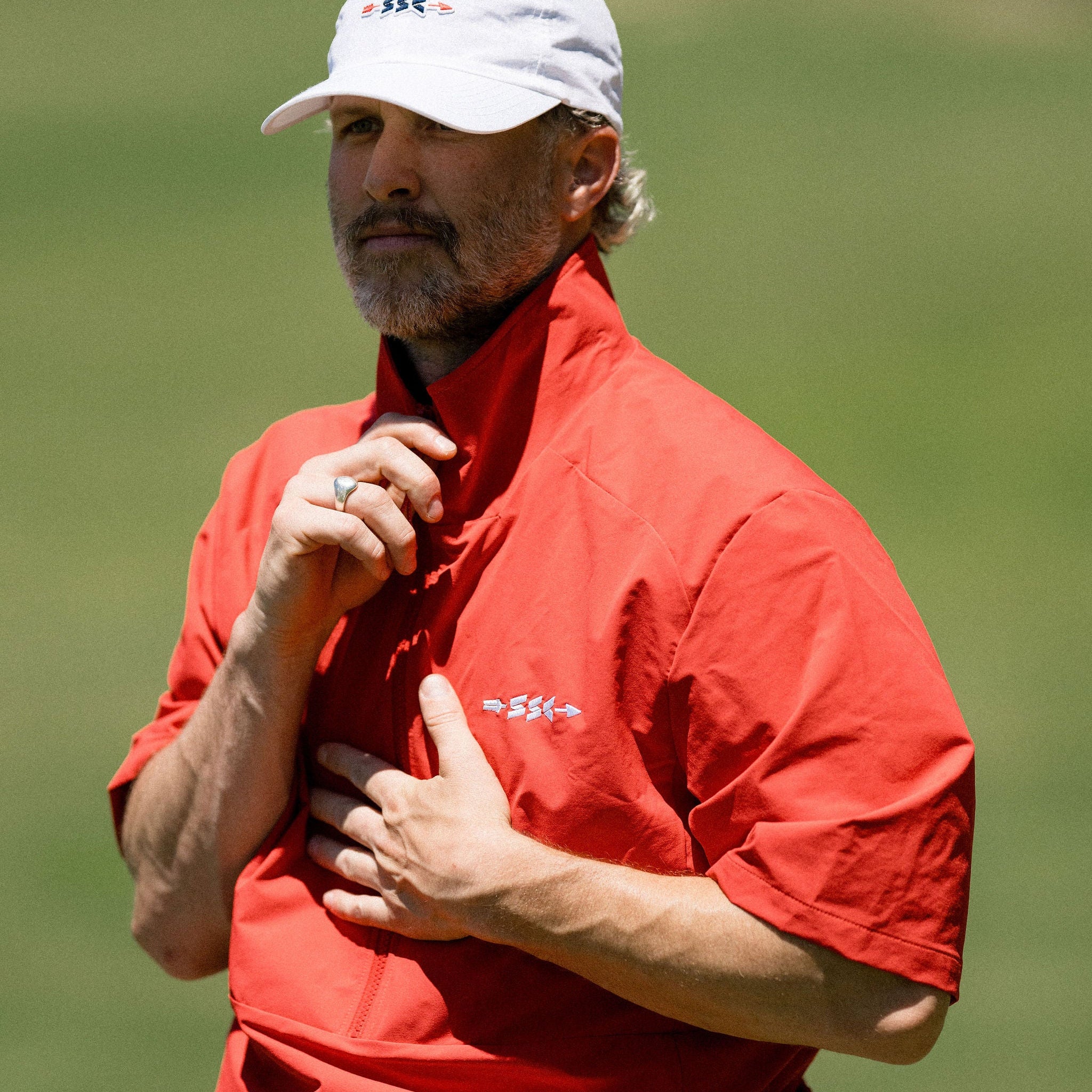 Man in a red shirt and white cap on a golf course