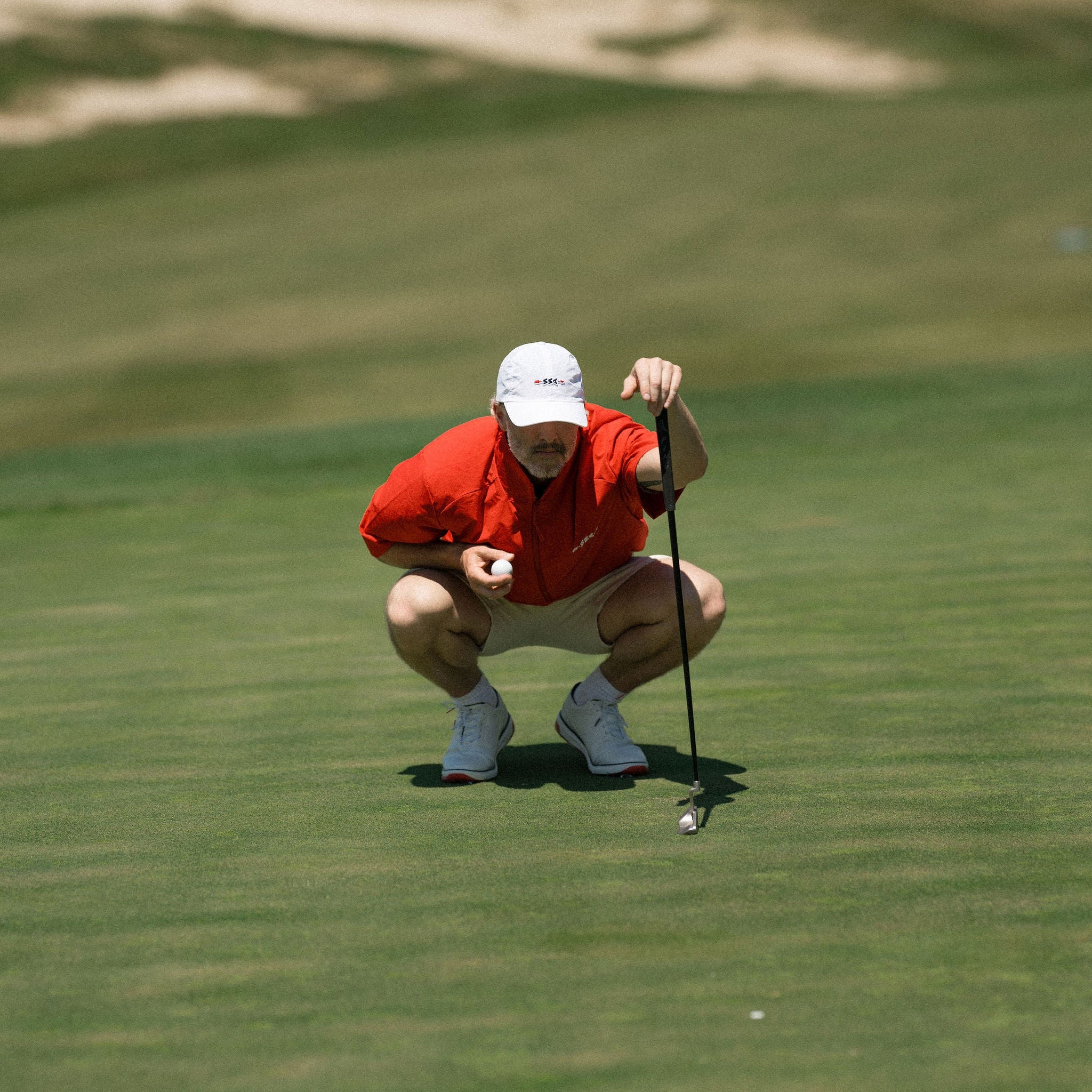 Golfer in red shirt and white cap on a golf course