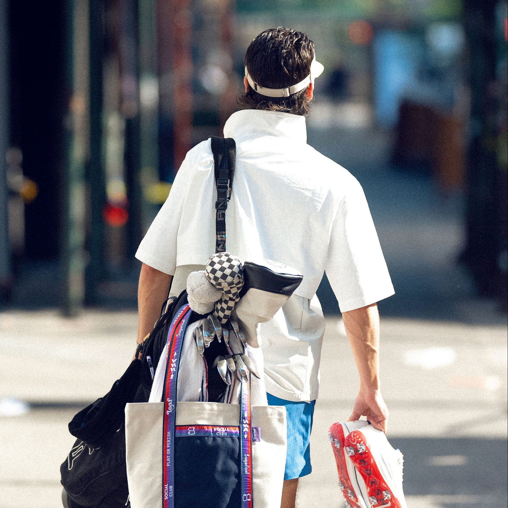 person walking in NYC with golf bag and visor